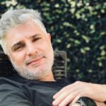 Close portrait of a relaxed adult man with gray hair reclining outdoors.